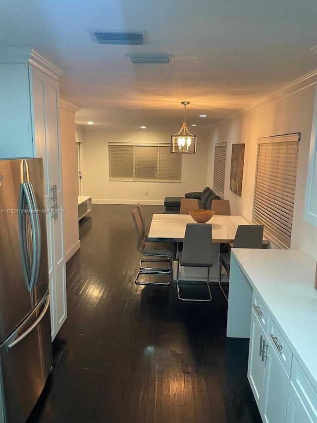dining room with baseboards, visible vents, dark wood finished floors, crown molding, and a notable chandelier