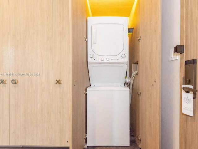 washroom featuring stacked washer / dryer and laundry area