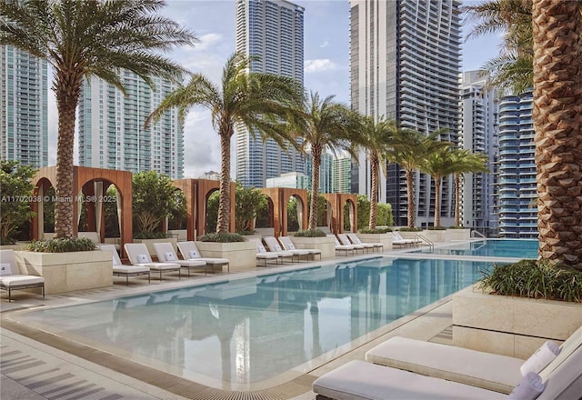 pool with a patio, fence, and a city view