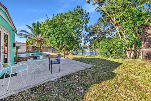 view of yard with a patio, a water view, and a fenced in pool