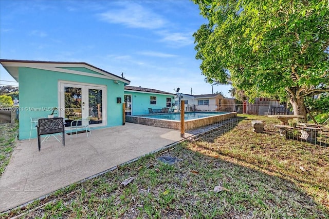 rear view of property featuring a fenced in pool and a patio area