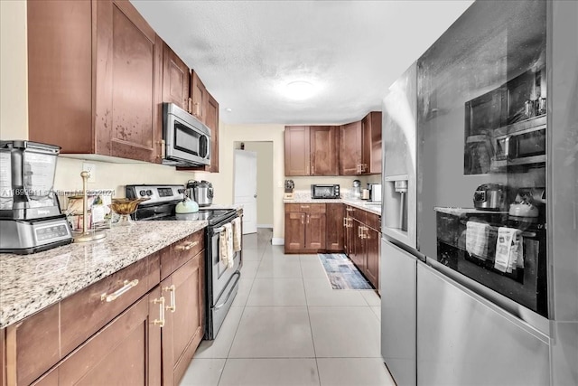 kitchen featuring light stone counters, light tile patterned floors, and appliances with stainless steel finishes