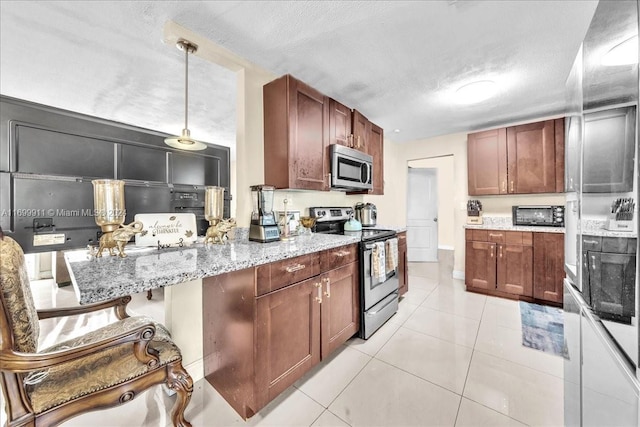 kitchen featuring a textured ceiling, light tile patterned floors, hanging light fixtures, and appliances with stainless steel finishes