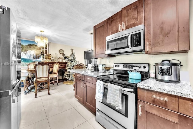 kitchen with stainless steel appliances, an inviting chandelier, light stone counters, pendant lighting, and a textured ceiling