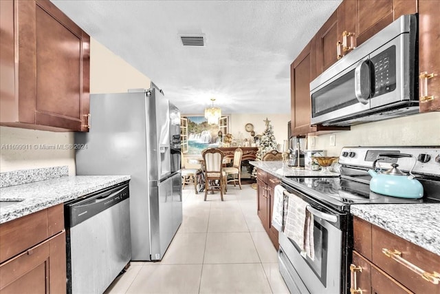 kitchen with light stone counters, light tile patterned flooring, stainless steel appliances, and a textured ceiling