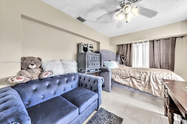 bedroom with ceiling fan, light tile patterned floors, and a textured ceiling