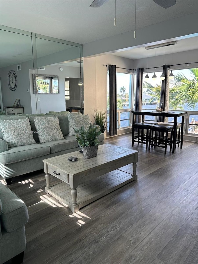 living room featuring a wealth of natural light, ceiling fan, and dark hardwood / wood-style floors