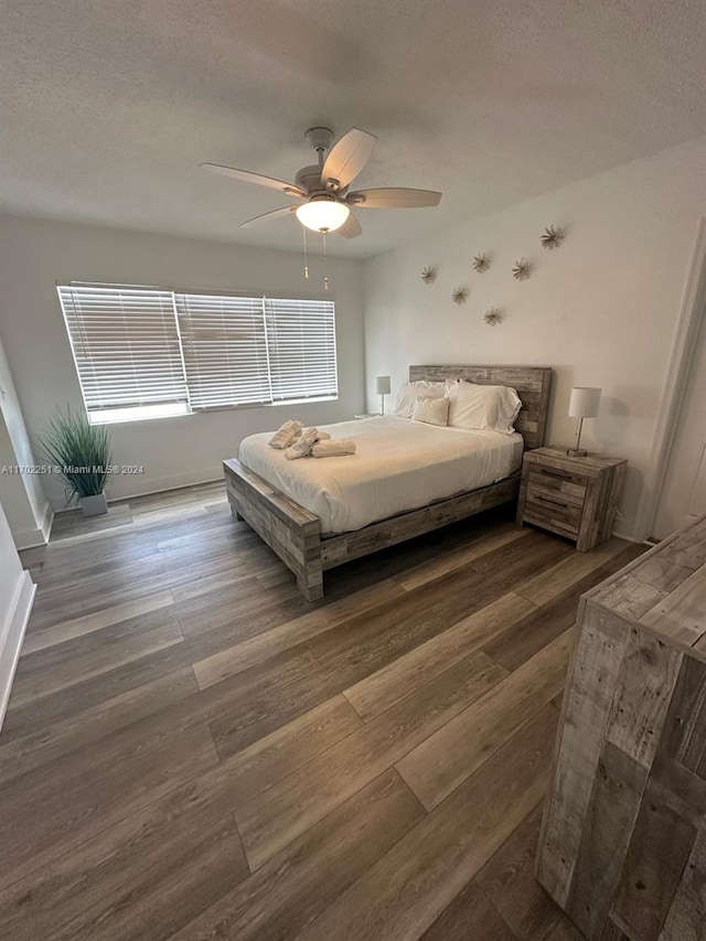 bedroom featuring dark hardwood / wood-style floors, ceiling fan, and a textured ceiling