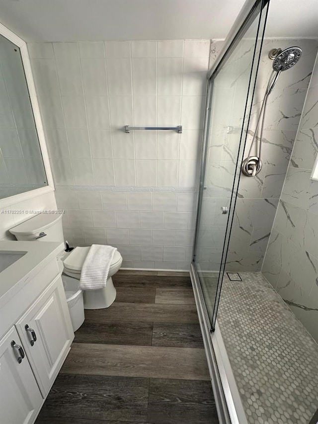 bathroom featuring hardwood / wood-style floors, vanity, toilet, and a shower with door