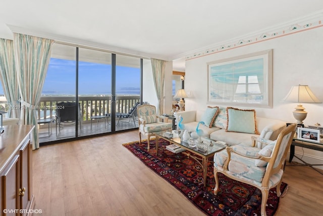 living room featuring a wealth of natural light, ornamental molding, and light wood-type flooring