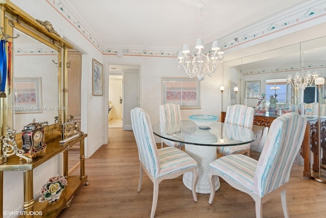 dining space with light hardwood / wood-style floors, a notable chandelier, and ornamental molding