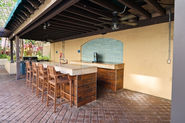 view of patio featuring ceiling fan and a bar