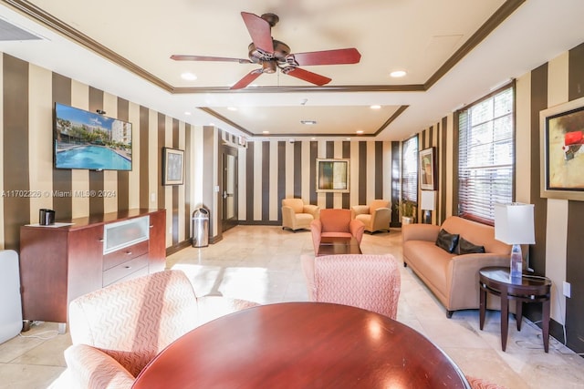 interior space with a raised ceiling, ceiling fan, ornamental molding, and light tile patterned flooring