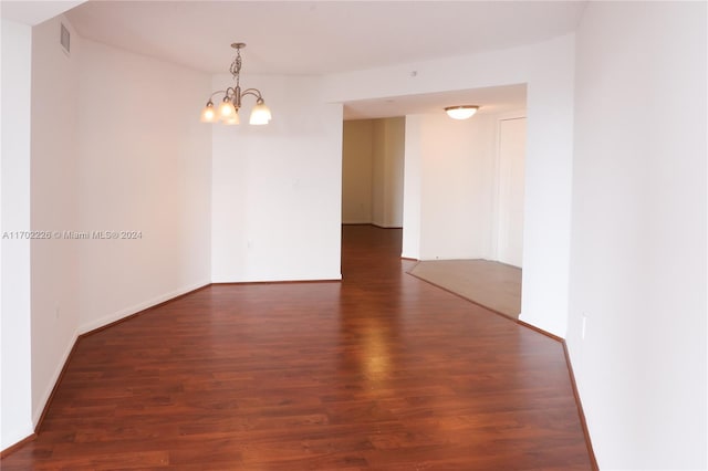 spare room with dark hardwood / wood-style floors and a chandelier