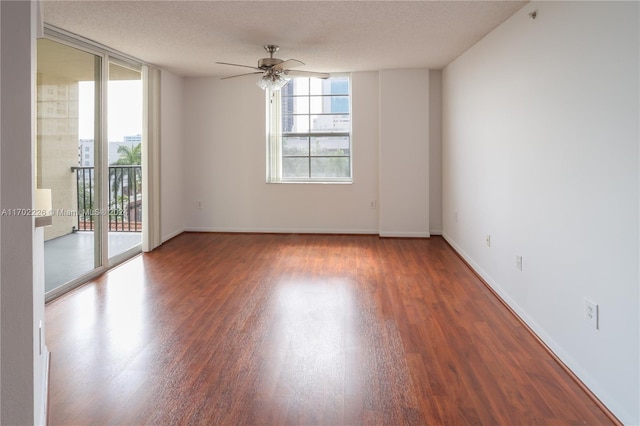 spare room featuring a textured ceiling, ceiling fan, expansive windows, and dark wood-type flooring