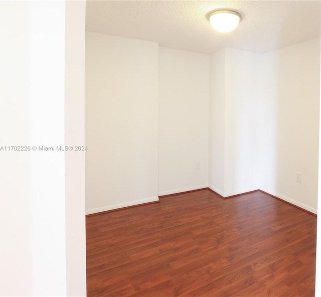 spare room featuring dark wood-type flooring and a textured ceiling