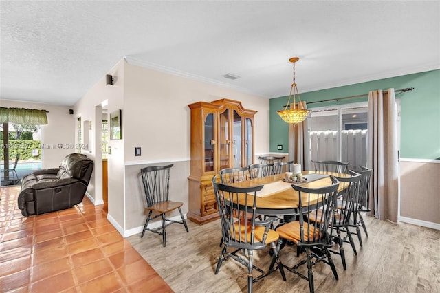 dining space featuring a chandelier, a textured ceiling, light wood-type flooring, and crown molding