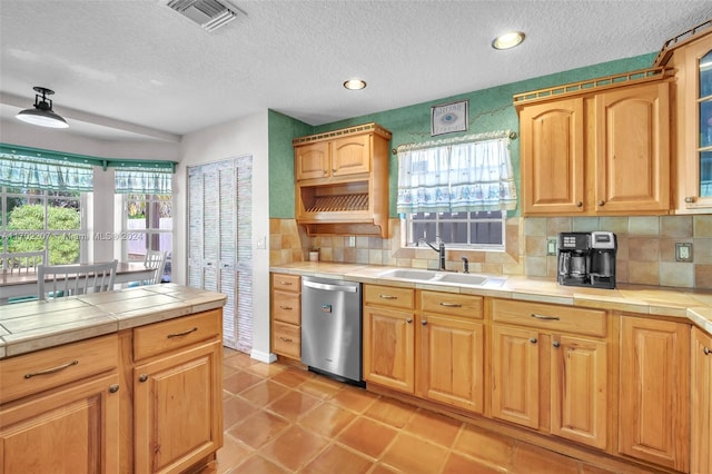 kitchen featuring dishwasher, decorative backsplash, tile countertops, and sink