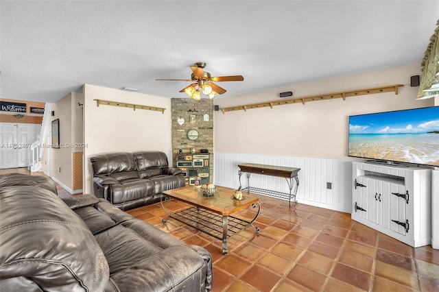 living room featuring ceiling fan and a textured ceiling