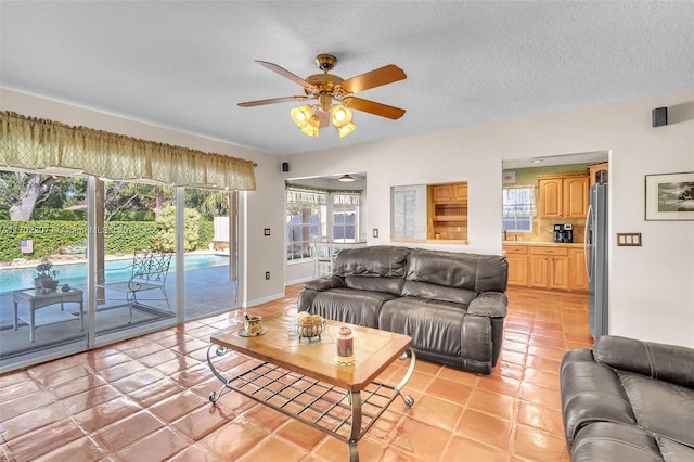 tiled living room featuring ceiling fan and a textured ceiling