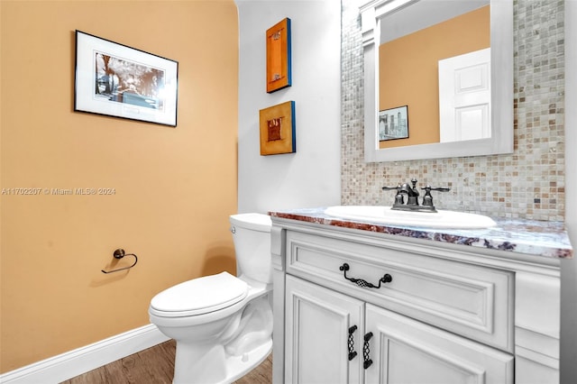 bathroom with hardwood / wood-style floors, vanity, tasteful backsplash, and toilet