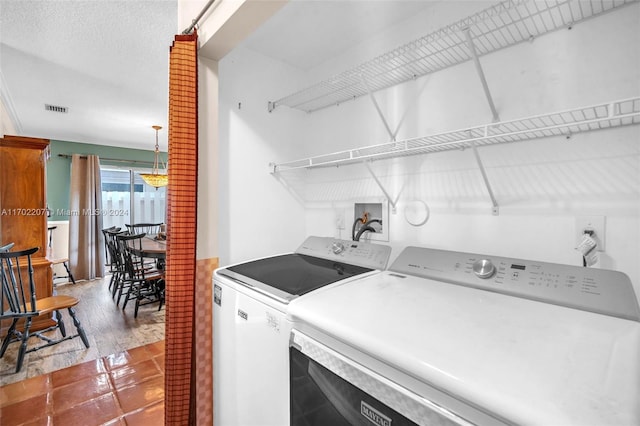 clothes washing area with a textured ceiling, hardwood / wood-style flooring, and washer and clothes dryer