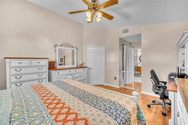 bedroom with ceiling fan, light hardwood / wood-style floors, a textured ceiling, and vaulted ceiling