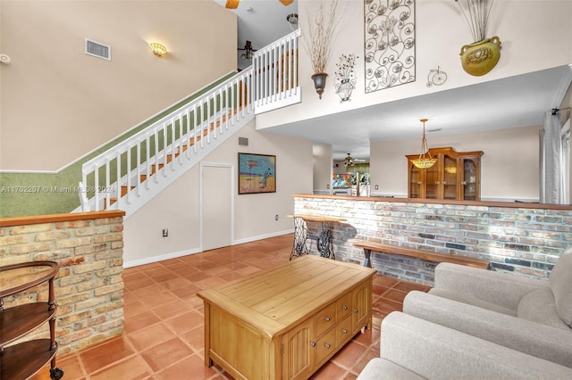 living room featuring a towering ceiling, ceiling fan, crown molding, and light tile patterned flooring