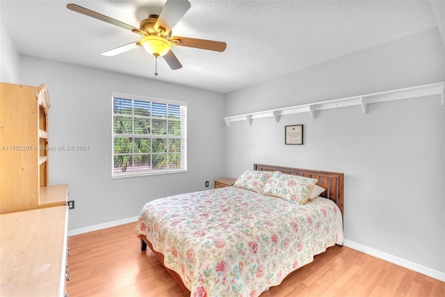 bedroom featuring hardwood / wood-style floors, ceiling fan, and a textured ceiling