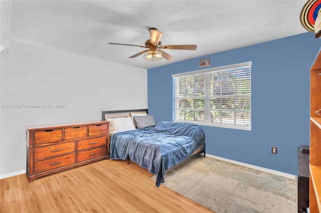 bedroom featuring ceiling fan, light wood-type flooring, and a textured ceiling