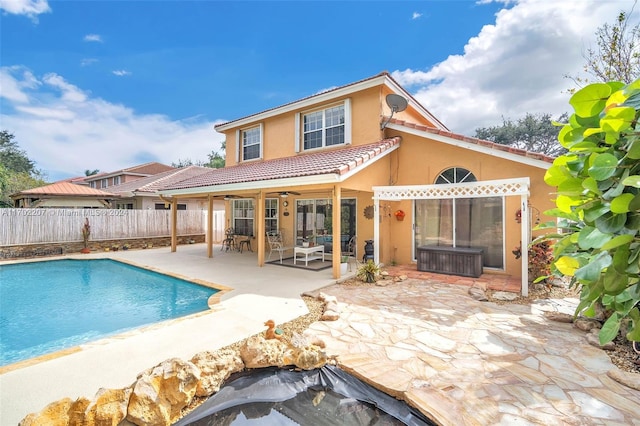 rear view of property with ceiling fan, a fenced in pool, and a patio