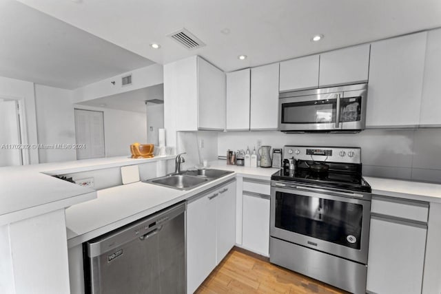 kitchen with white cabinetry, sink, stainless steel appliances, and light hardwood / wood-style floors