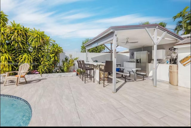 view of patio with area for grilling, an outdoor bar, and ceiling fan