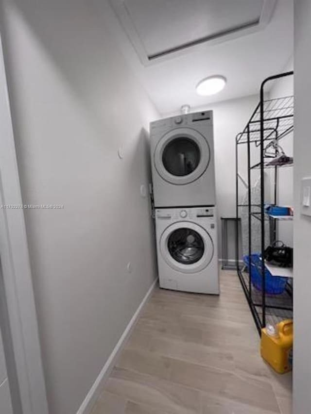 washroom with stacked washing maching and dryer and light hardwood / wood-style floors