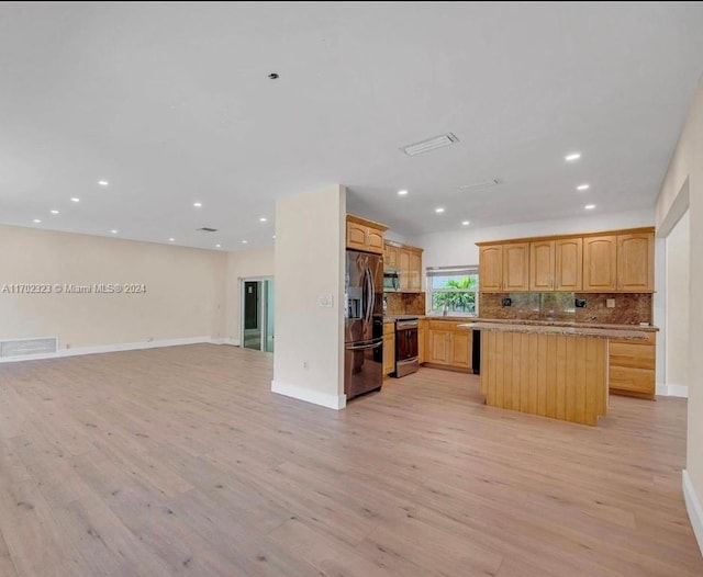 kitchen with light stone countertops, appliances with stainless steel finishes, decorative backsplash, a kitchen island, and light wood-type flooring