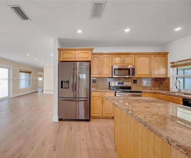 kitchen featuring light stone counters, sink, stainless steel appliances, and light hardwood / wood-style flooring