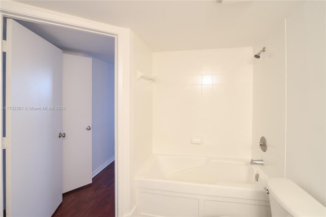 bathroom featuring tiled shower / bath combo, toilet, and wood-type flooring