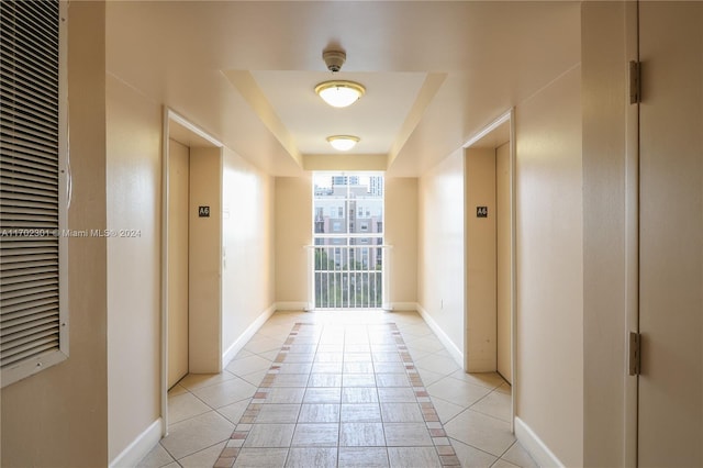 corridor featuring elevator and light tile patterned floors