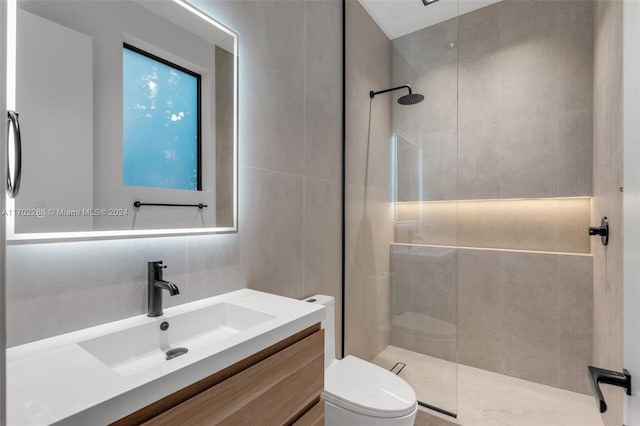 bathroom with tasteful backsplash, a tile shower, vanity, tile walls, and toilet