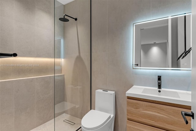 bathroom featuring vanity, toilet, tiled shower, and tile walls