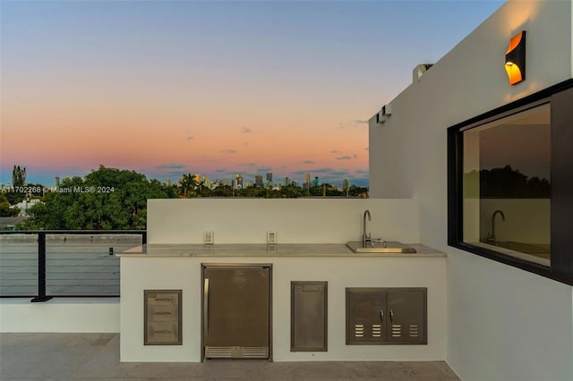 patio terrace at dusk with sink and an outdoor kitchen