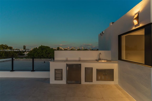 patio terrace at dusk with sink and exterior kitchen