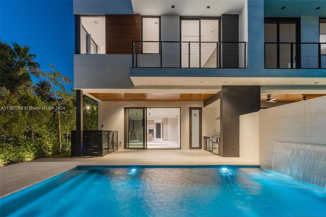 rear view of house featuring a patio, pool water feature, a balcony, and area for grilling