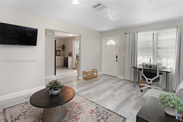 foyer entrance featuring light hardwood / wood-style flooring and a textured ceiling