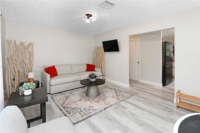 living room with a textured ceiling and light wood-type flooring