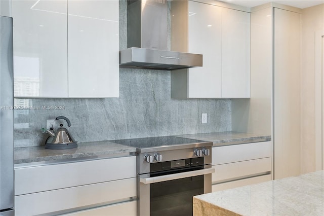 kitchen featuring white cabinetry, stainless steel range with electric cooktop, and wall chimney range hood