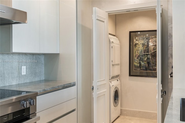 clothes washing area featuring light tile patterned floors and stacked washer and clothes dryer