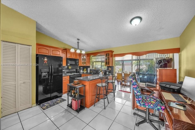 kitchen with black appliances, vaulted ceiling, decorative backsplash, light tile patterned floors, and a breakfast bar area