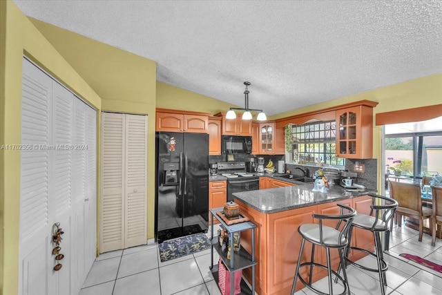 kitchen with black appliances, decorative backsplash, kitchen peninsula, and light tile patterned floors