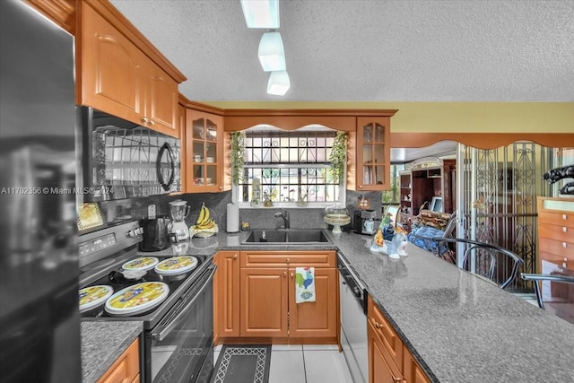 kitchen with sink, a textured ceiling, decorative backsplash, light tile patterned floors, and black appliances